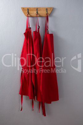 Red aprons hanging on hook