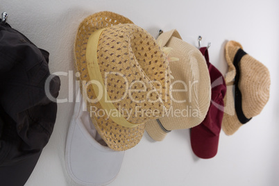 Various straw hats and caps hanging on hook