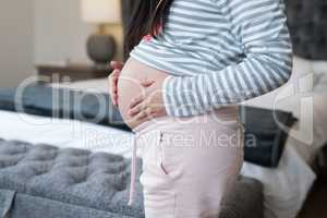 Mid section of pregnant woman touching her stomach