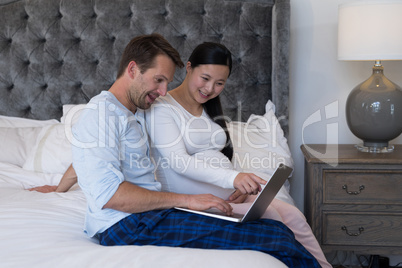 Couple using laptop in bedroom Couple using laptop in bedroom