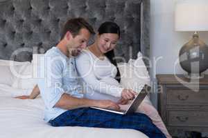 Couple using laptop in bedroom