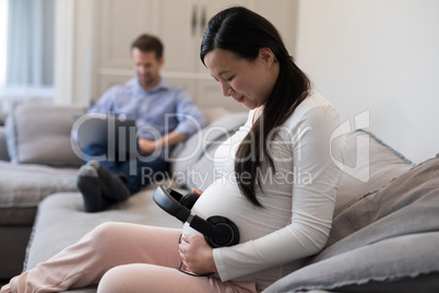 Pregnant woman placing headphones on her stomach