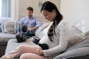 Pregnant woman placing headphones on her stomach