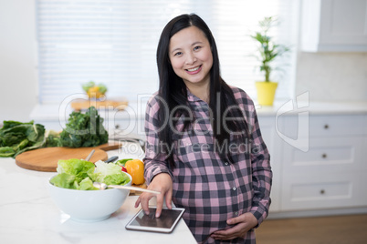 Pregnant woman using digital tablet in kitchen