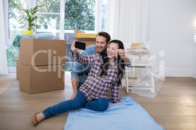 Pregnant couple holding key and taking selfie in new house