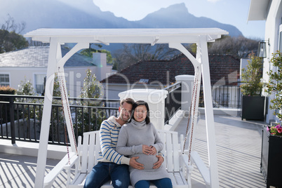 Man and pregnant woman touching her belly in balcony