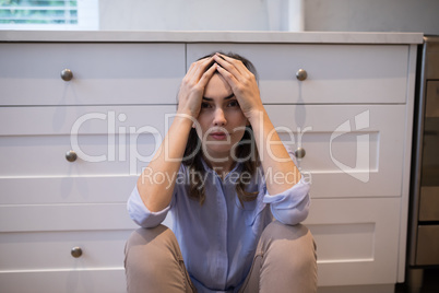 Worried woman sitting in kitchen