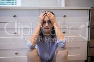 Worried woman sitting in kitchen