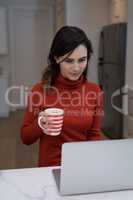 Woman using laptop while having coffee