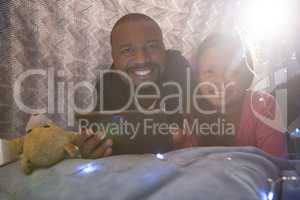 Father and daughter using digital tablet in bedroom