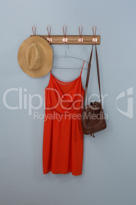Red dress, hat and bag hanging on hook