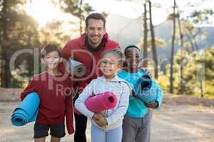 Portrait of coach and kids standing with yoga mat