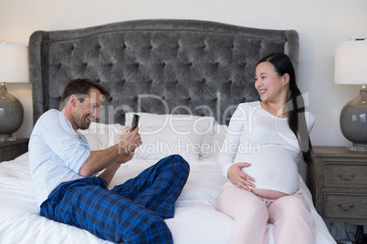 Man taking picture of woman with mobile phone