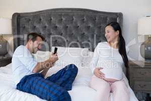 Man taking picture of woman with mobile phone