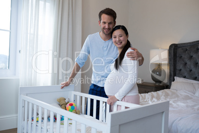 Happy couple standing near cot