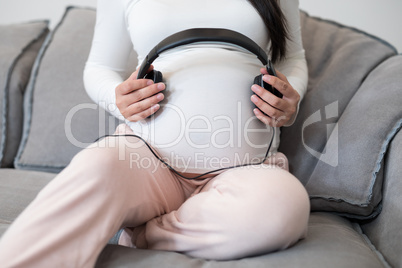 Pregnant woman placing headphones on her stomach