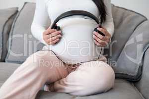 Pregnant woman placing headphones on her stomach