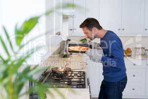 Man smelling baked pizza in kitchen
