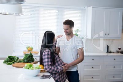 Man touching womans pregnant belly in the kitchen