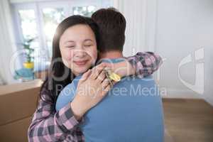 Couple embracing each other while holding keys of new home