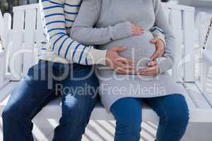 Man and pregnant woman touching her belly in the balcony