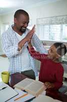 Father and son giving high five to each other in kitchen