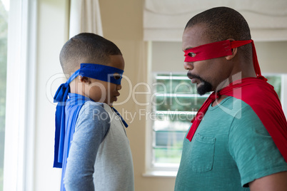 Father and son in superhero costume looking face to face