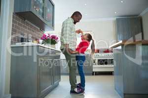 Father and daughter dancing together in kitchen