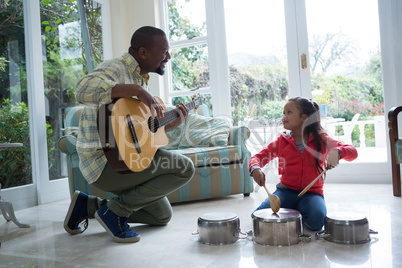 Father and daughter playing with guitar and utensils in living room