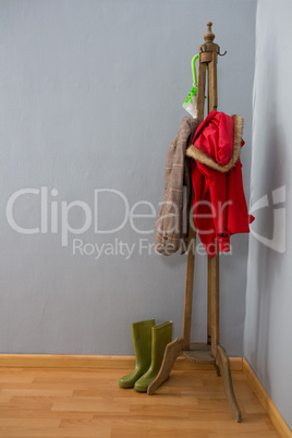 Umbrella, warm clothing and wellington boots on wooden stand