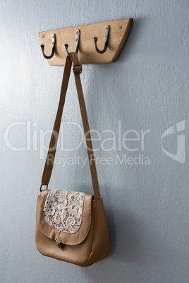 Stylish handbag hanging on hook
