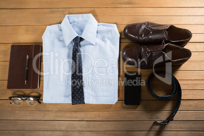 Folded shirt and accessories arranged on wooden plank