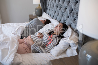 Thoughtful pregnant woman relaxing in bedroom