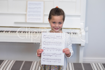 Portrait of cute girl standing with musical sheet