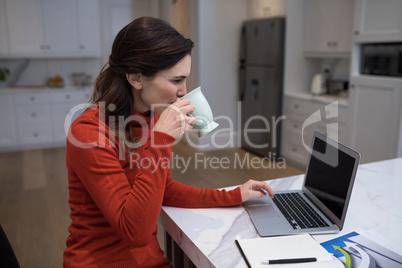 Beautiful woman using laptop while having coffee