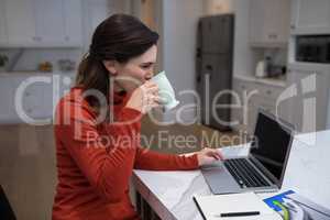 Beautiful woman using laptop while having coffee