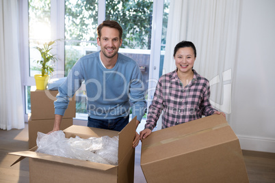 Smiling couple with cardboard boxes sitting at their new home