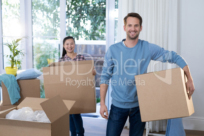 Couple carrying big cardboard box at new home