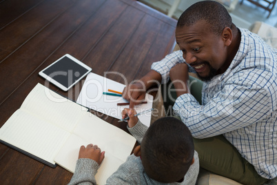 Father helping his son with homework in living room