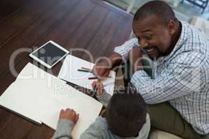Father helping his son with homework in living room