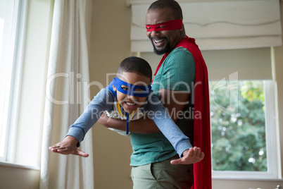 Son and father pretending to be a superhero at home