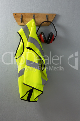 Protective workwear and earmuffs hanging on hook