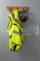 Protective workwear and earmuffs hanging on hook