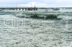 a storm at sea, the waves cover the pier