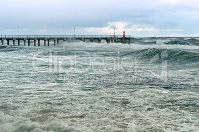 a storm at sea, the waves cover the pier