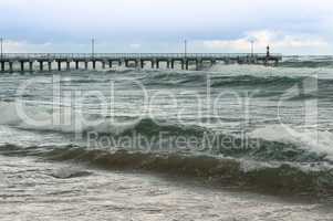 a storm at sea, the waves cover the pier