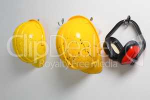 Hard hats and earmuffs hanging on hook