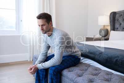 Thoughtful man sitting on bed