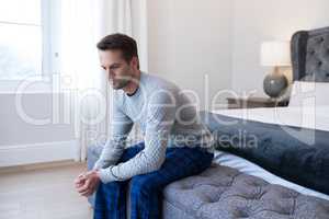 Thoughtful man sitting on bed