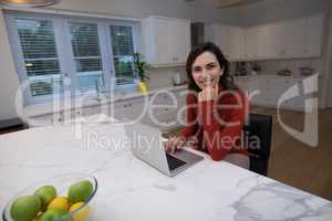 Woman using laptop in kitchen